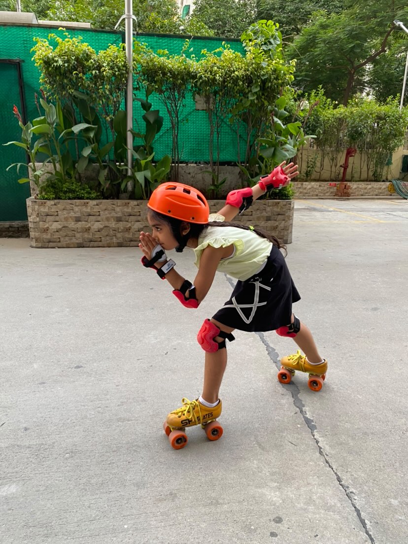 Young girl in skater skirt roller skating on ground. 